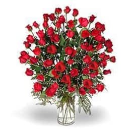 Tall arrangement of many red roses in a clear glass vase