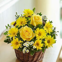 Yellow roses and daisies arranged in a wicker basket