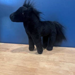 Black plush horse figurine on a wooden surface