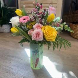 Mixed bouquet of roses, tulips, and a pink gerbera in a decorated vase