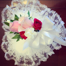 Pink and white roses arranged with lace and a white ribbon