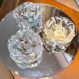 Three glittery glass rose-shaped ornaments on a mirrored tray