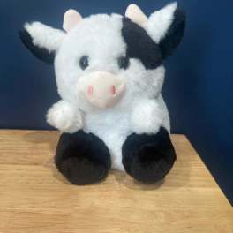 Plush black-and-white cow sitting on a wooden surface