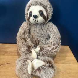 Plush sloth toy sitting on a wooden surface