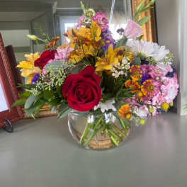 Mixed bouquet with red roses and colorful flowers in a glass vase