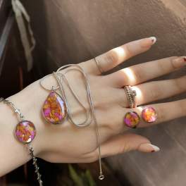 Hand wearing colorful resin jewelry with silver chains and rings