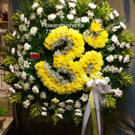 Large standing wreath of yellow and white flowers with ribbon