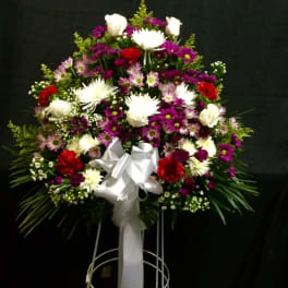 Standing floral spray with white, purple, and red flowers on a white easel