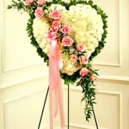 Heart-shaped floral spray with pink roses and white flowers on a stand