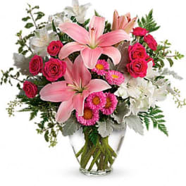 Pink lilies and roses arranged in a clear glass vase