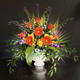 Bright mixed flower arrangement in a white urn vase