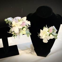 Pair of floral corsages with white and pale pink flowers on black display stands