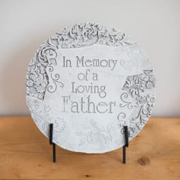 Round memorial plaque reading "In Memory of a Loving Father" on a stand