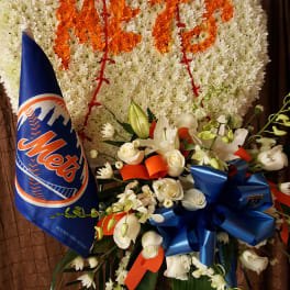 Large white floral wreath with orange lettering and a Mets pennant