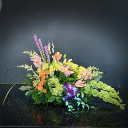 Low floral arrangement with pink, yellow, orange, and purple blooms