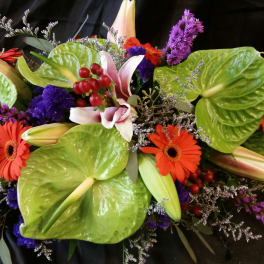 Mixed bouquet with orange gerbera daisies, lilies, and purple flowers