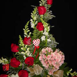 Tall floral arrangement with red roses and pink blooms on a black background