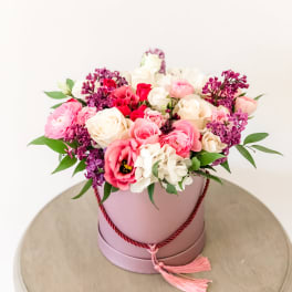 Pink and white rose arrangement in a round hatbox