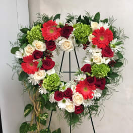 Heart-shaped floral wreath with red roses, white daisies, and green hydrangeas