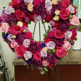 Heart-shaped standing wreath of pink and purple roses and chrysanthemums on an easel