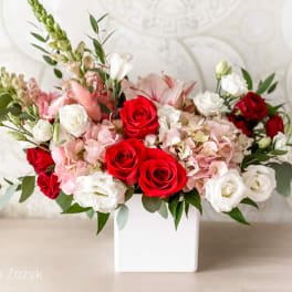 Red and white roses with pink blooms in a white vase