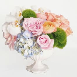 Pastel flower arrangement in a white pedestal vase