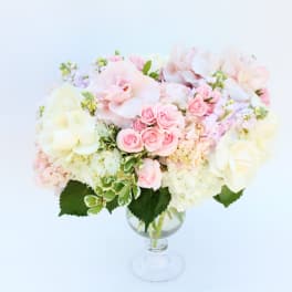 Pastel bouquet of pink and cream flowers in a clear glass vase