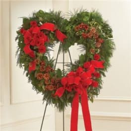 Heart-shaped holiday wreath with red bows on a stand