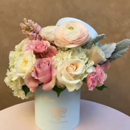 Pastel bouquet of roses, ranunculus, and hydrangeas in a light blue box