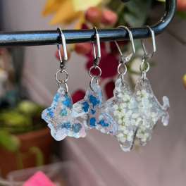 Three glittery fish-shaped earrings hang from a black rod.