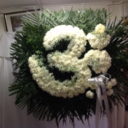 Large white floral funeral wreath with a ribbon bow