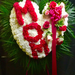 Heart-shaped floral tribute with red and white flowers and a pink ribbon