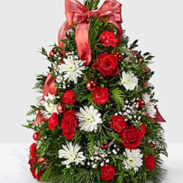 Red and white floral arrangement shaped like a Christmas tree with a ribbon bow