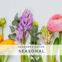Stems of yellow, purple, and pink seasonal flowers laid in a row on a white background