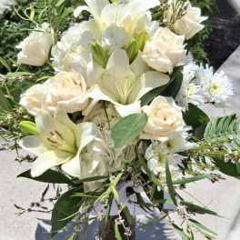 White lilies and cream roses arranged in a glass vase