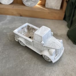 White pickup truck-shaped planter on a concrete floor