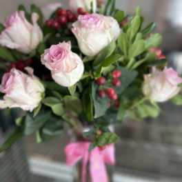 Bouquet of pale pink roses with red berries and a pink ribbon