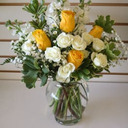 Yellow and white roses arranged in a clear glass vase