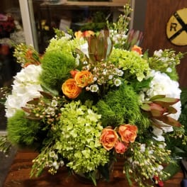 Large bouquet of orange roses, white hydrangeas, and green blooms in a glass vase