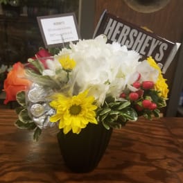 Bouquet of mixed flowers with a Hershey's chocolate bar in a black vase