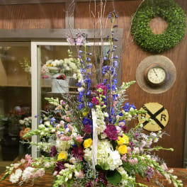 Large mixed flower arrangement in a wicker basket with tall branches