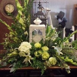 Large green and white floral arrangement with a lantern centerpiece