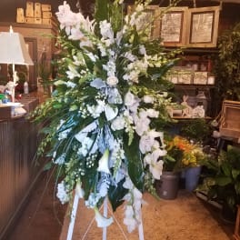 Tall white floral standing spray on a white easel