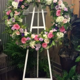 Large floral wreath on a white easel with pink, white, and purple flowers