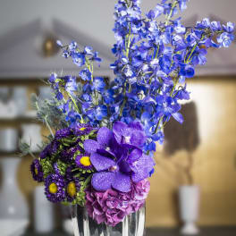 Purple and blue floral arrangement in a silver vase
