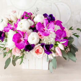 Pink, white, and purple floral arrangement in a white wooden box