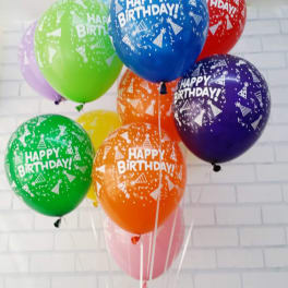 Cluster of colorful birthday balloons against a white brick wall