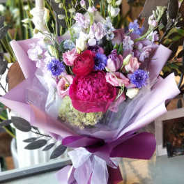 Bouquet of pink, purple, and white flowers wrapped in lavender paper