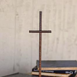 Rustic metal cross standing on a wooden base with a stone accent