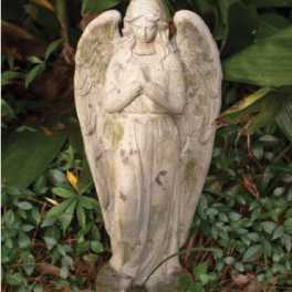 Stone angel statue standing among garden plants
